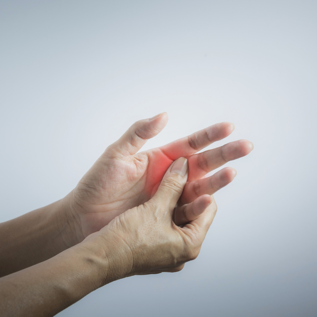 A person holding their hand with a red area highlighting pain or discomfort in the fingers against a plain background.