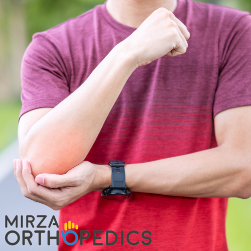 Person in a red shirt holding their elbow with the other hand, wearing a black watch. Text on image reads "Mirza Orthopedics.
