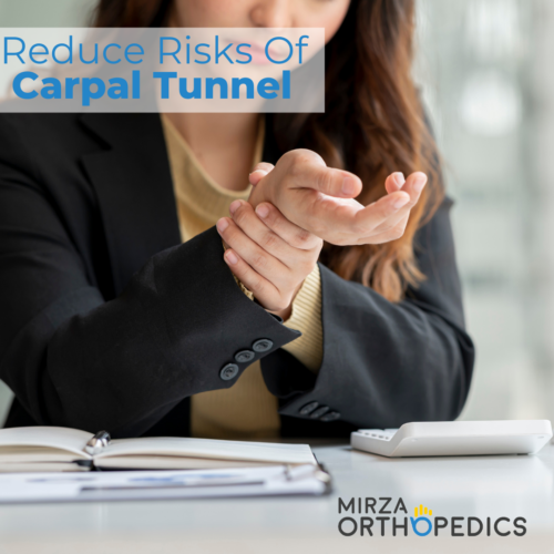 Person in a blazer holding their wrist, suggesting discomfort. Open notebook, pen, and small device on desk. Text: "Reduce Risks Of Carpal Tunnel." Logo: Mirza Orthopedics.